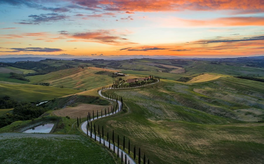 Camino entre campos verdes y colinas de la Toscana al atardecer